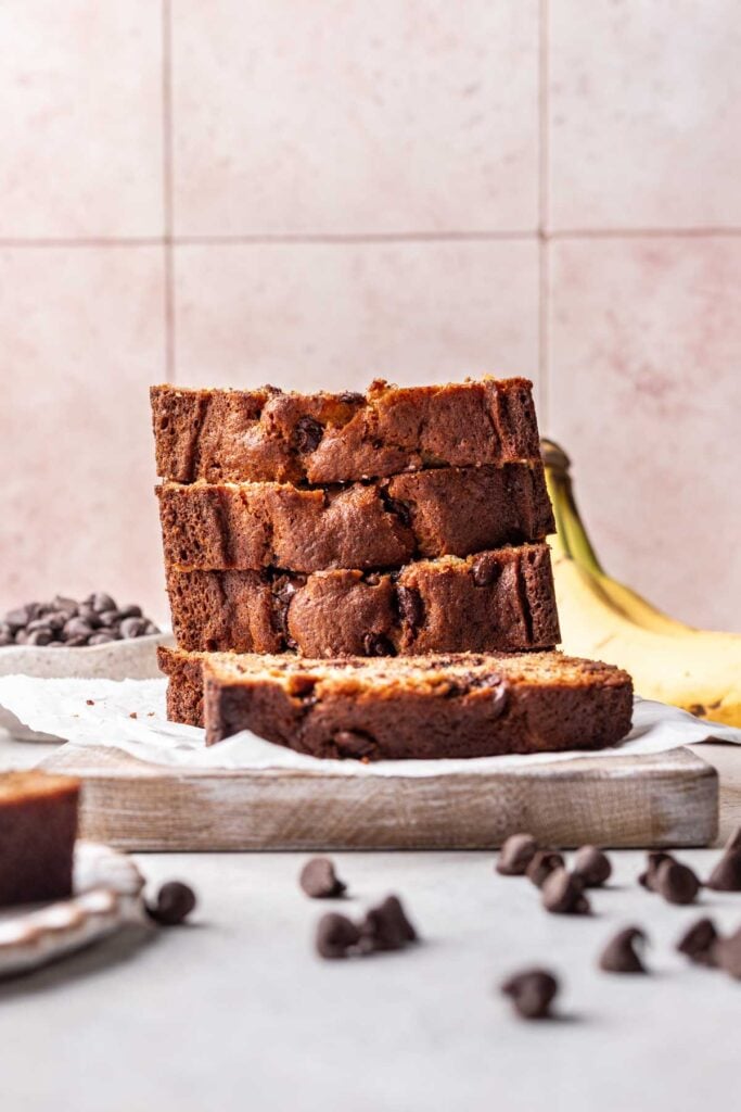 3 slices of banana bread piled on top of each other on a wood board