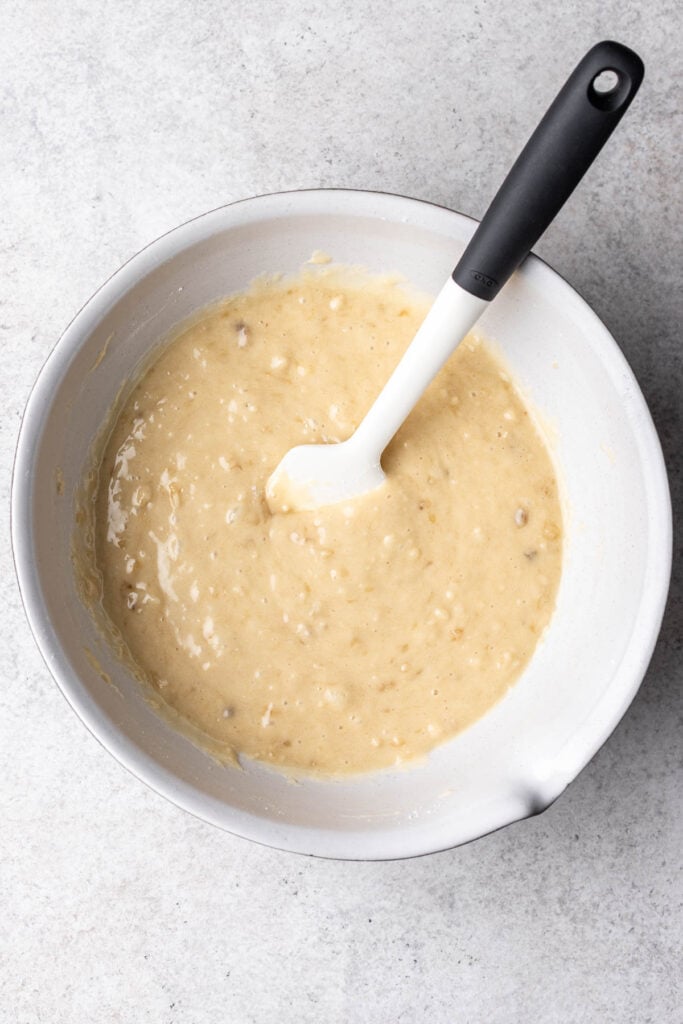 banana bread batter in a white bowl with a spatula