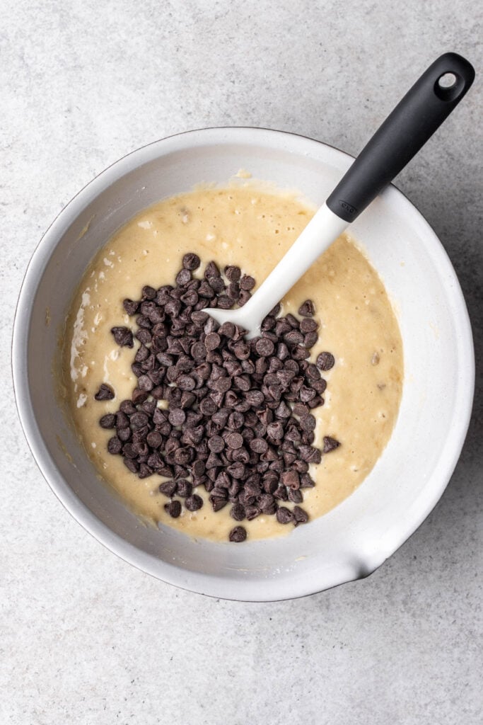 banana bread batter with chocolate chips in a white bowl with a spatula