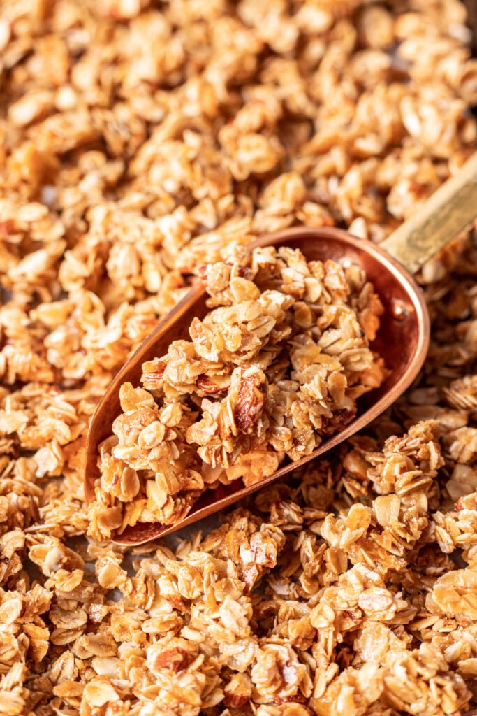 granola on a sheet pan with a scooper