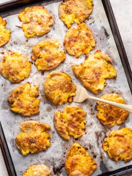 crispy smashed potatoes on a sheet pan with a fork