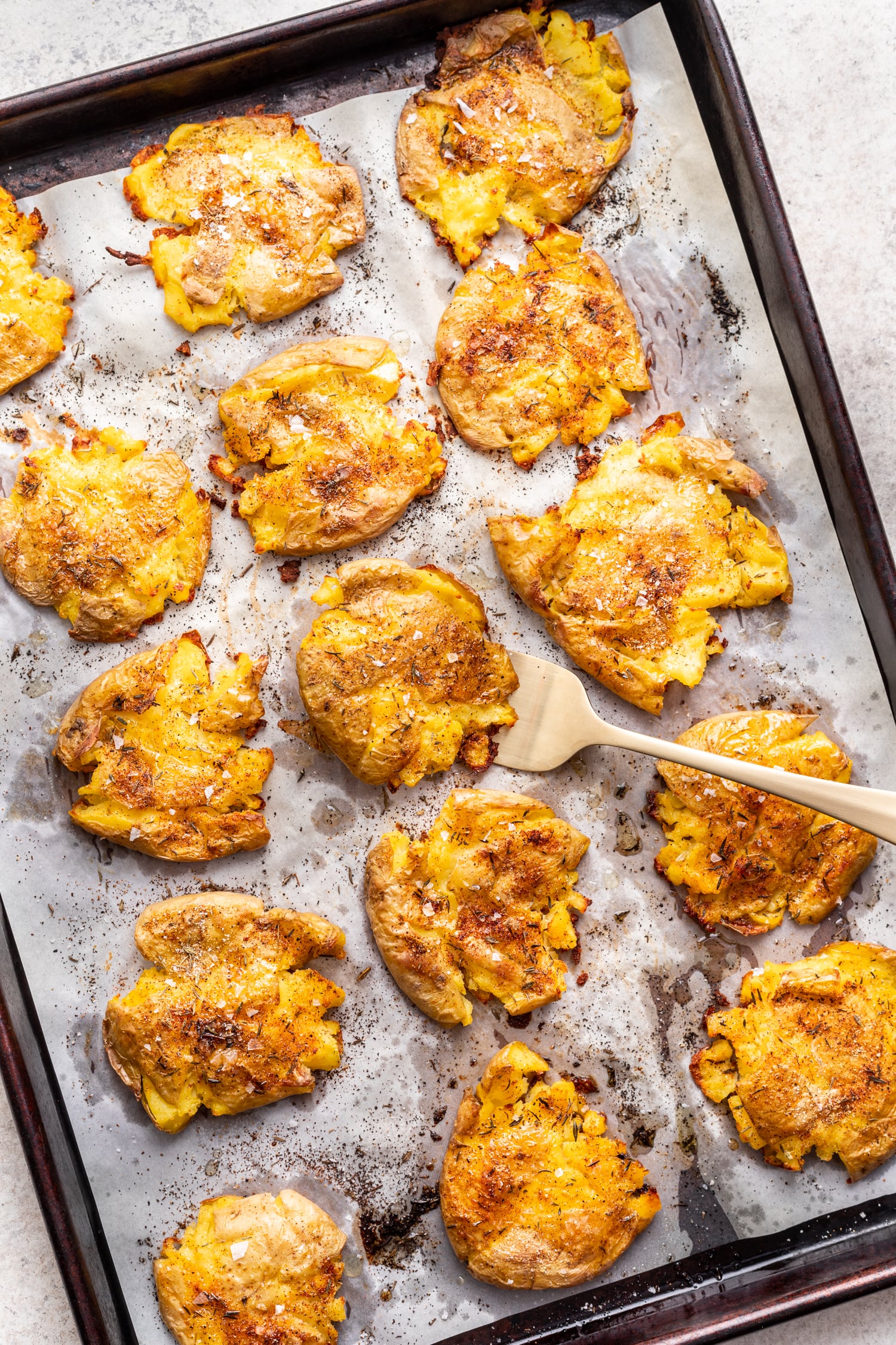 crispy smashed potatoes on a sheet pan with a fork