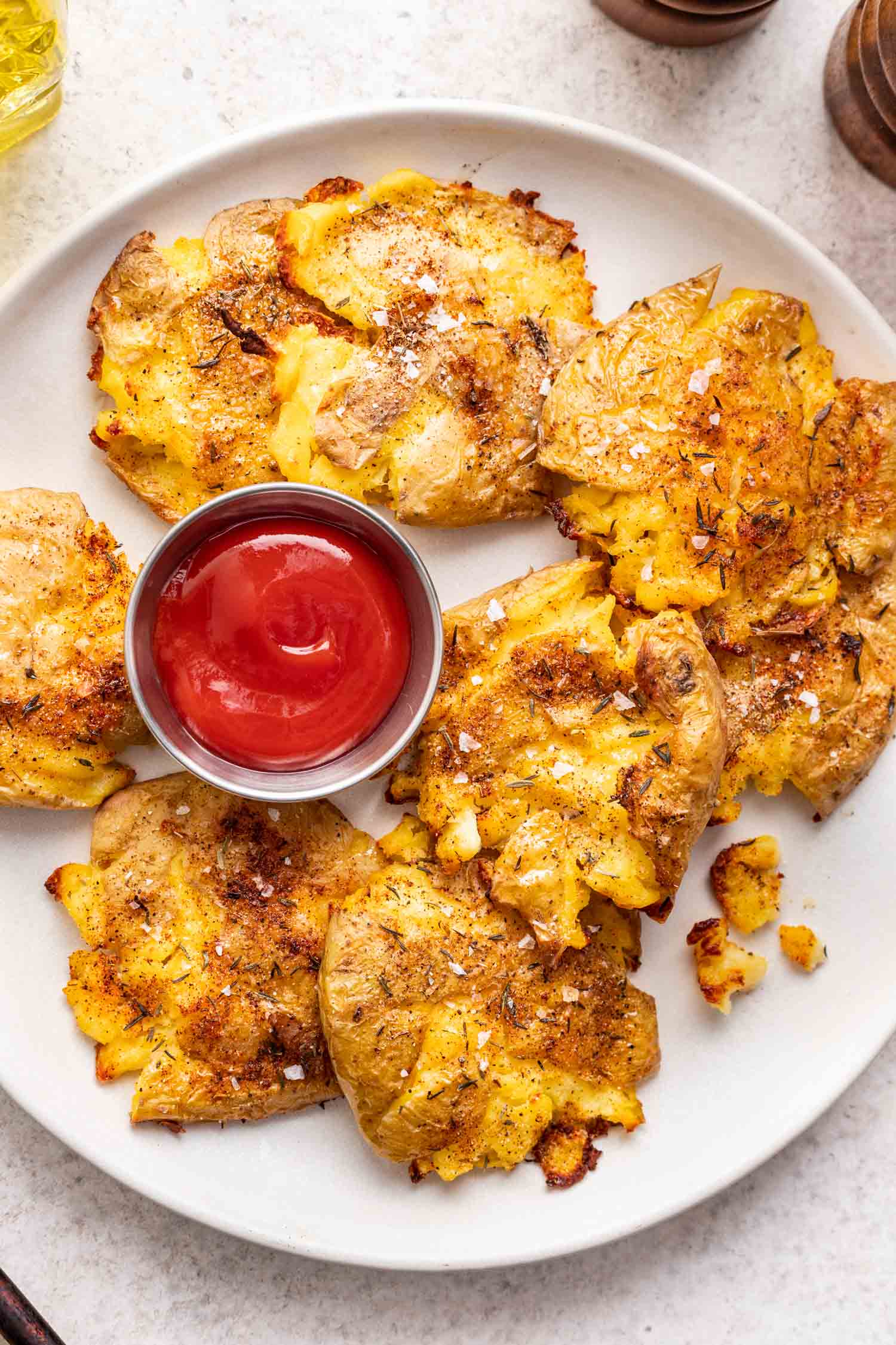 crispy smashed potatoes on a plate with a bowl of ketchup