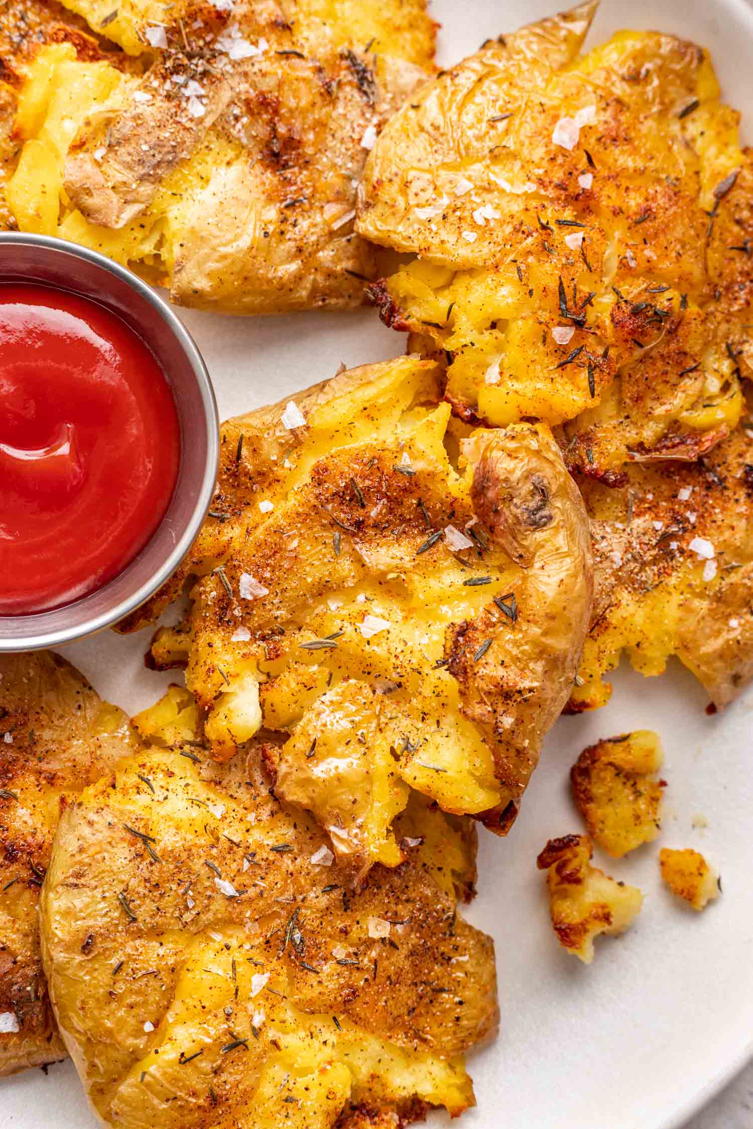 crispy smashed potatoes on a plate with a bowl of ketchup