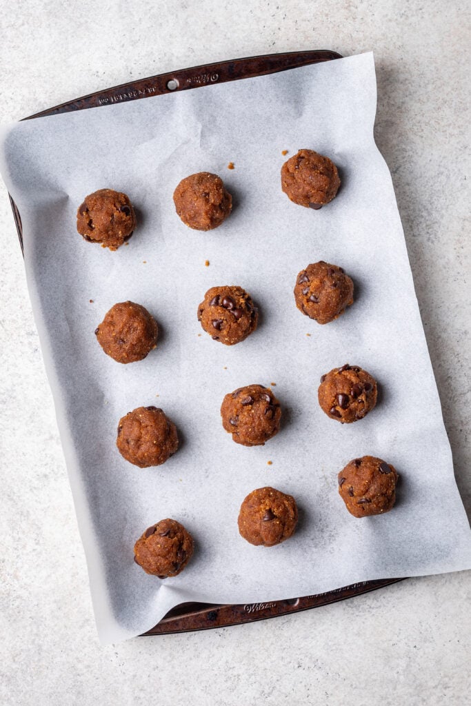 cookie dough balls on a parchment lined sheet pan