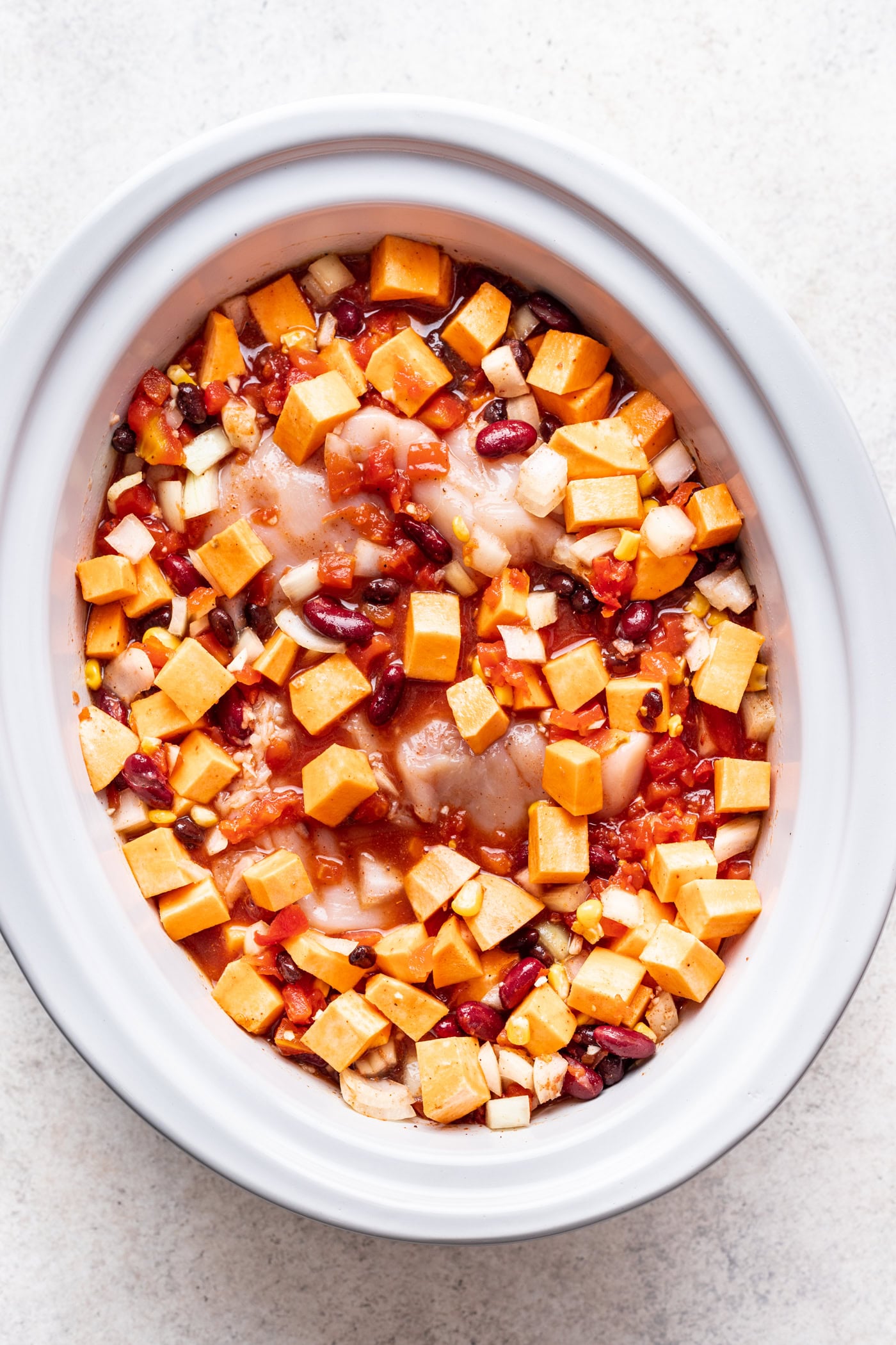 chopped veggies, raw chicken and broth in a slow cooker