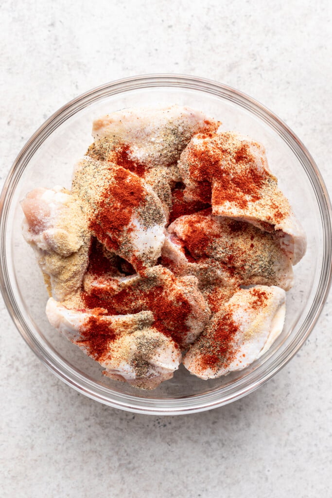 raw chicken wings in a clear bowl with spices