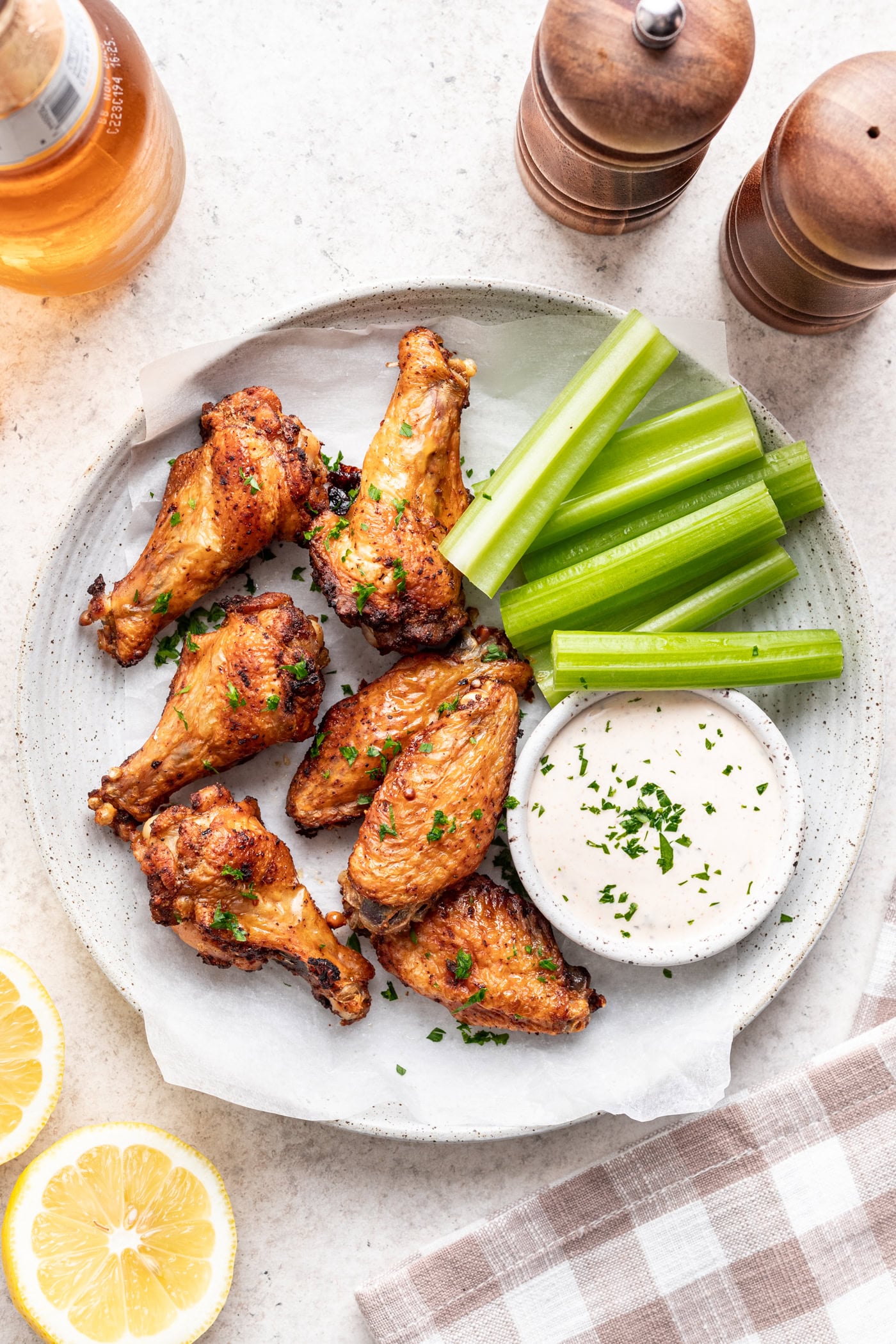 chicken wings on a plate with celery sticks and yogurt dipping sauce