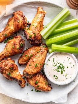 chicken wings on a plate with celery sticks and yogurt dipping sauce