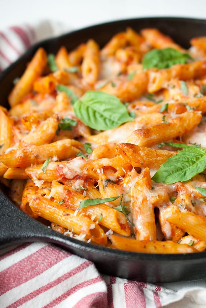 skillet with melted cheese over cooked pasta