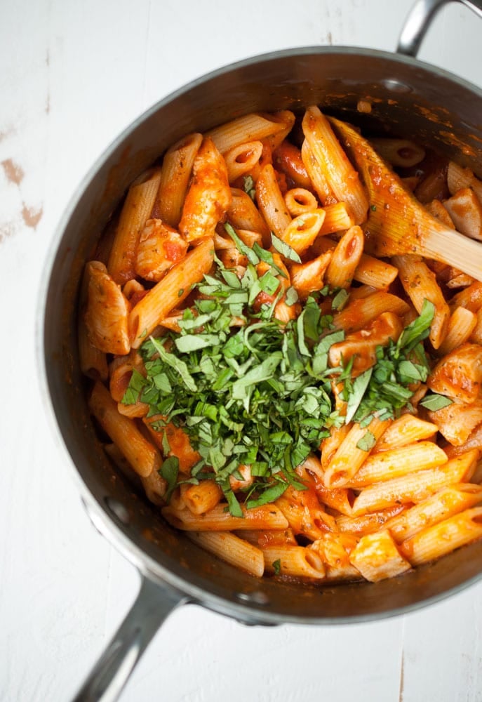 pot with penne, tomato sauce and chopped basil