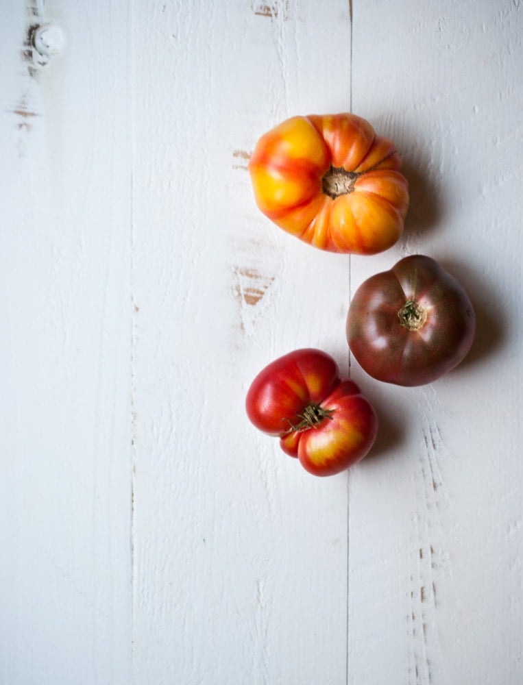 3 heirloom tomatoes on a white board