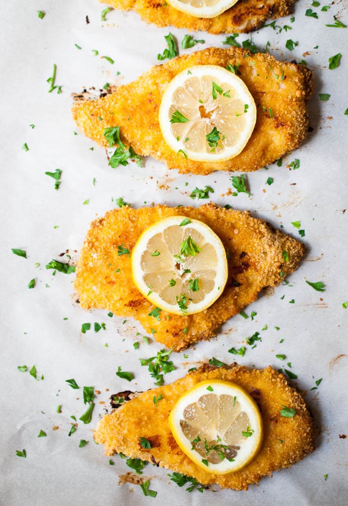 Crispy Buttermilk Baked Chicken on a sheet pan with lemon slices on top
