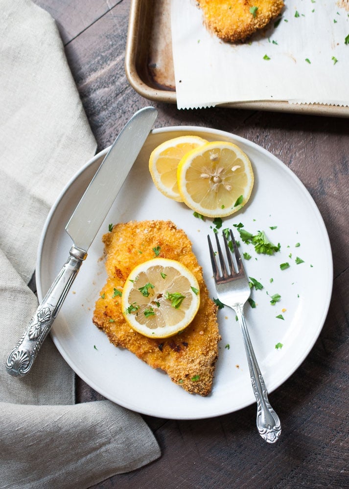 breaded piece of chicken with a knife and fork on a plate