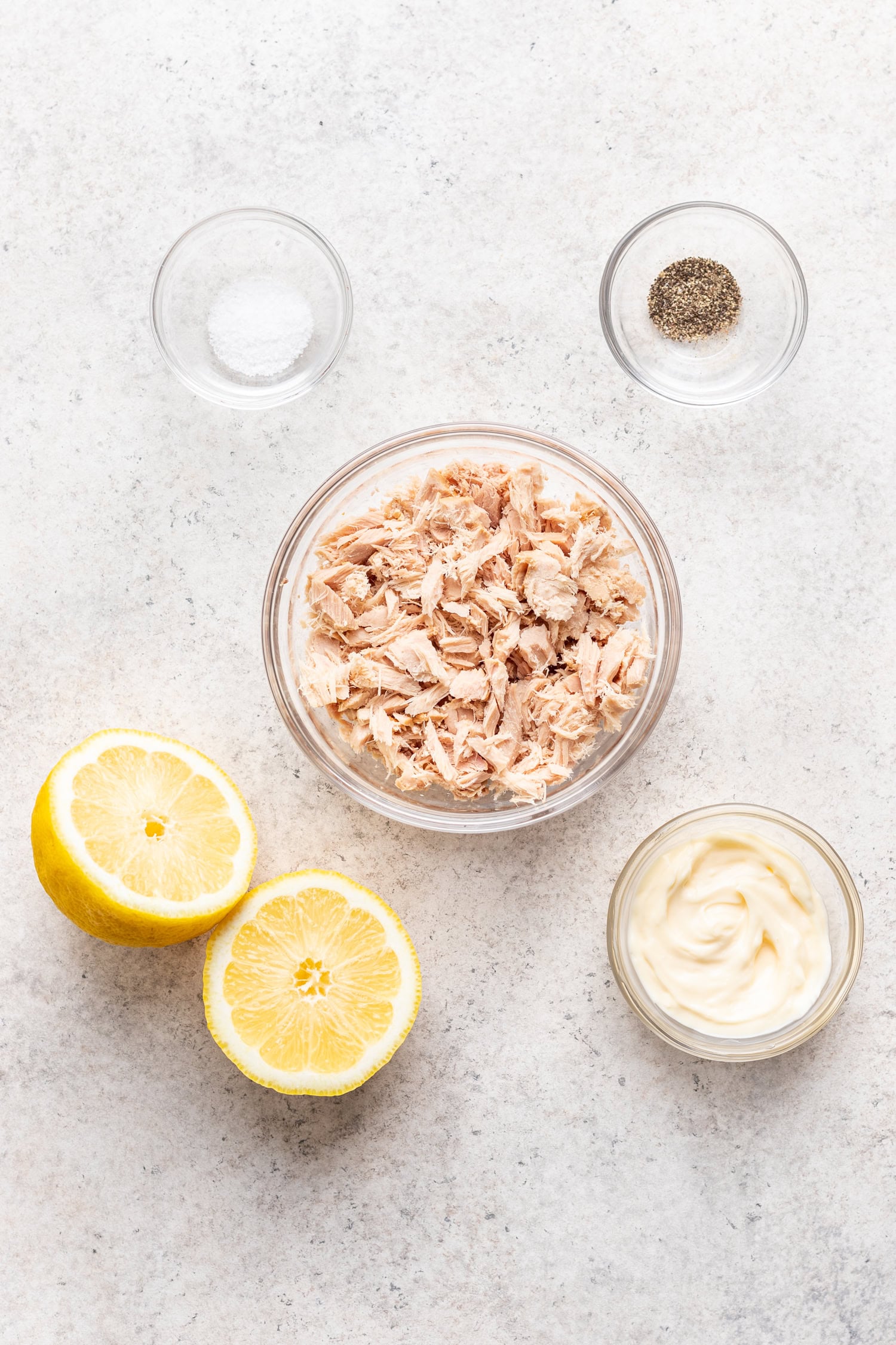 bowl of tuna,lemon and bowl of mayonnaise on a grey board