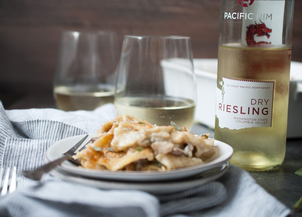 Mushroom Sage Lasagna on a plate with a fork and a glass of wine in the background