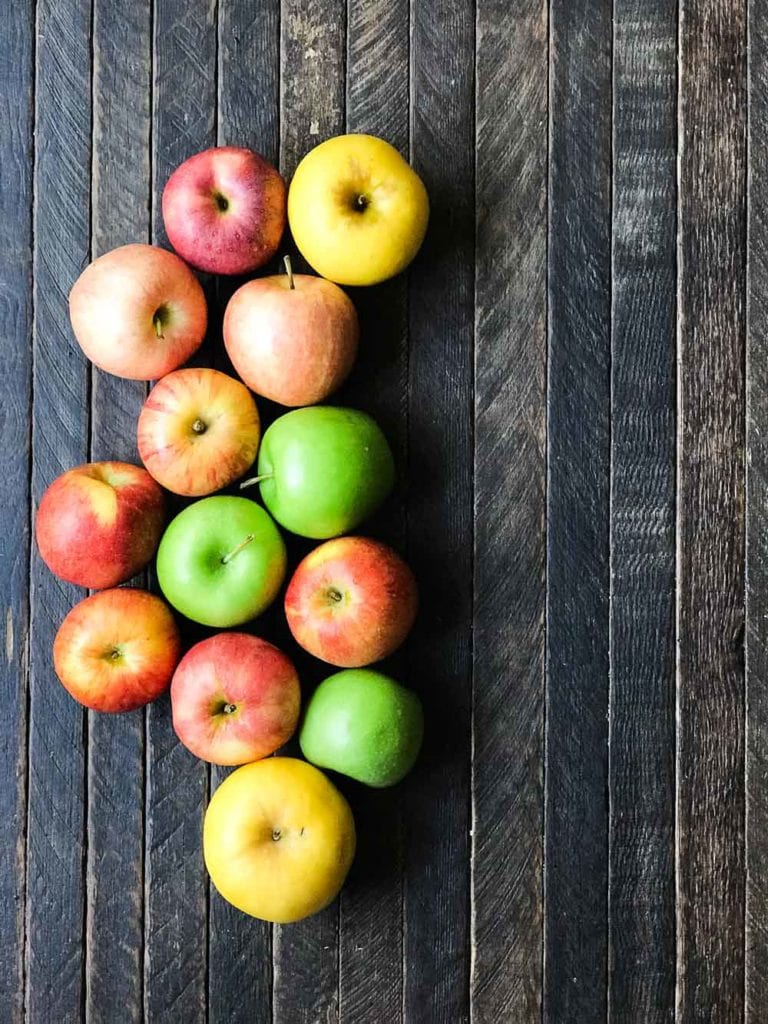 overhead shot of 13 apples on a wood plank board