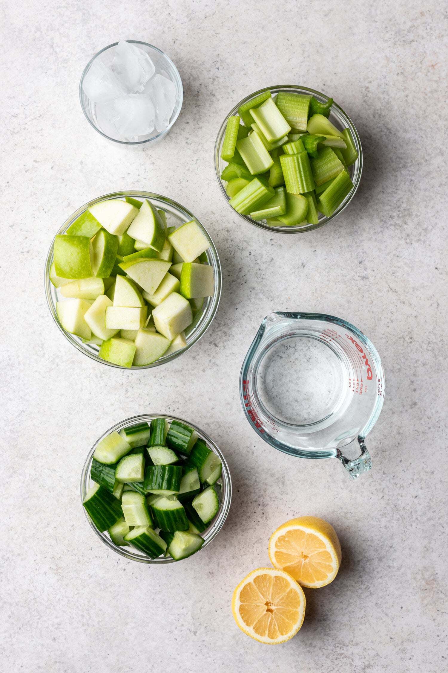 ingredients in bowls like apple, cucumber, water and celery