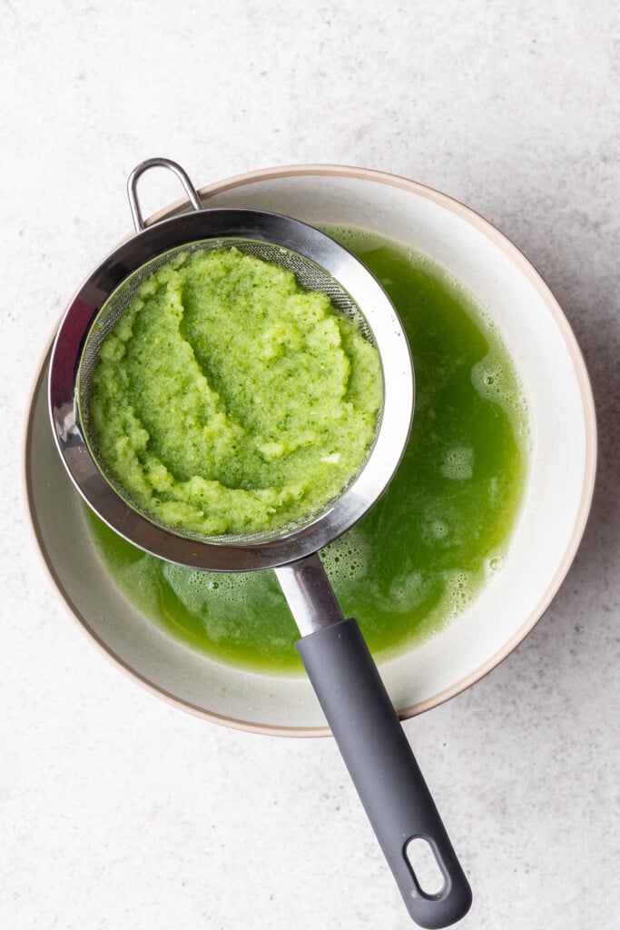 green juice pulp in a strainer over a bowl
