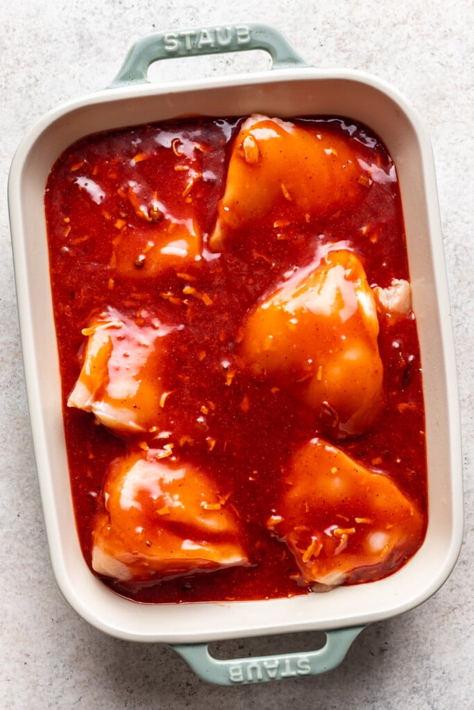 baking dish with raw chicken and red sauce