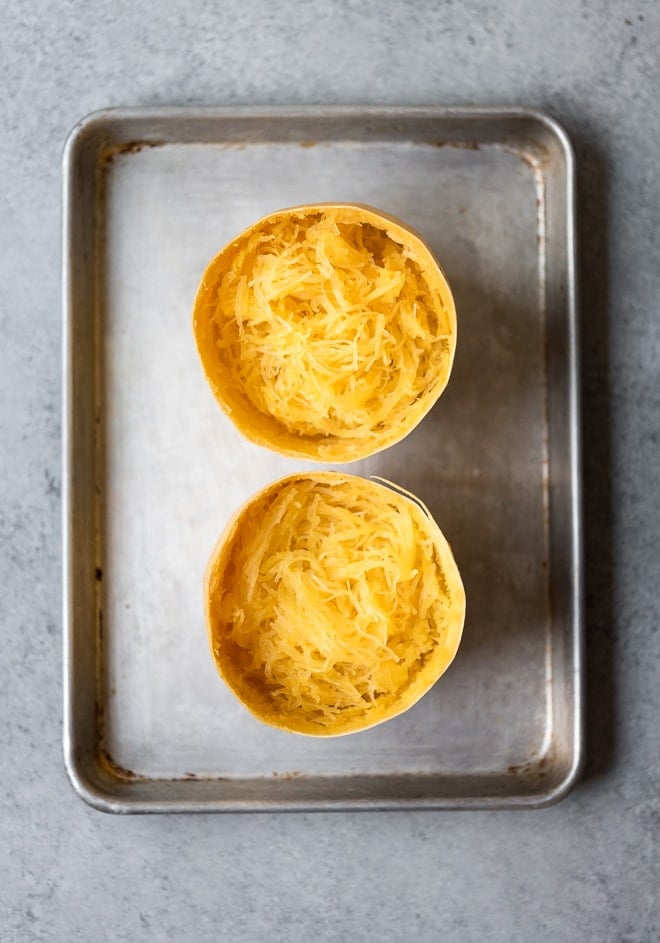 Overhead shot of spaghetti squash cut in half with noodles cooked and scraped