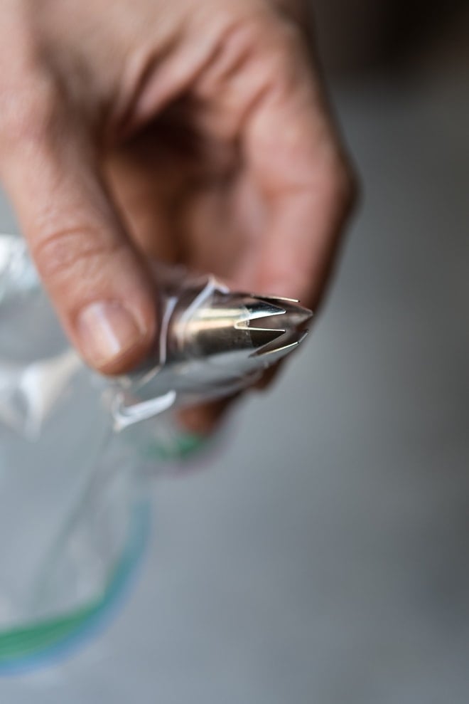 Hand holding a plastic bag with a piping tip inserted and close up