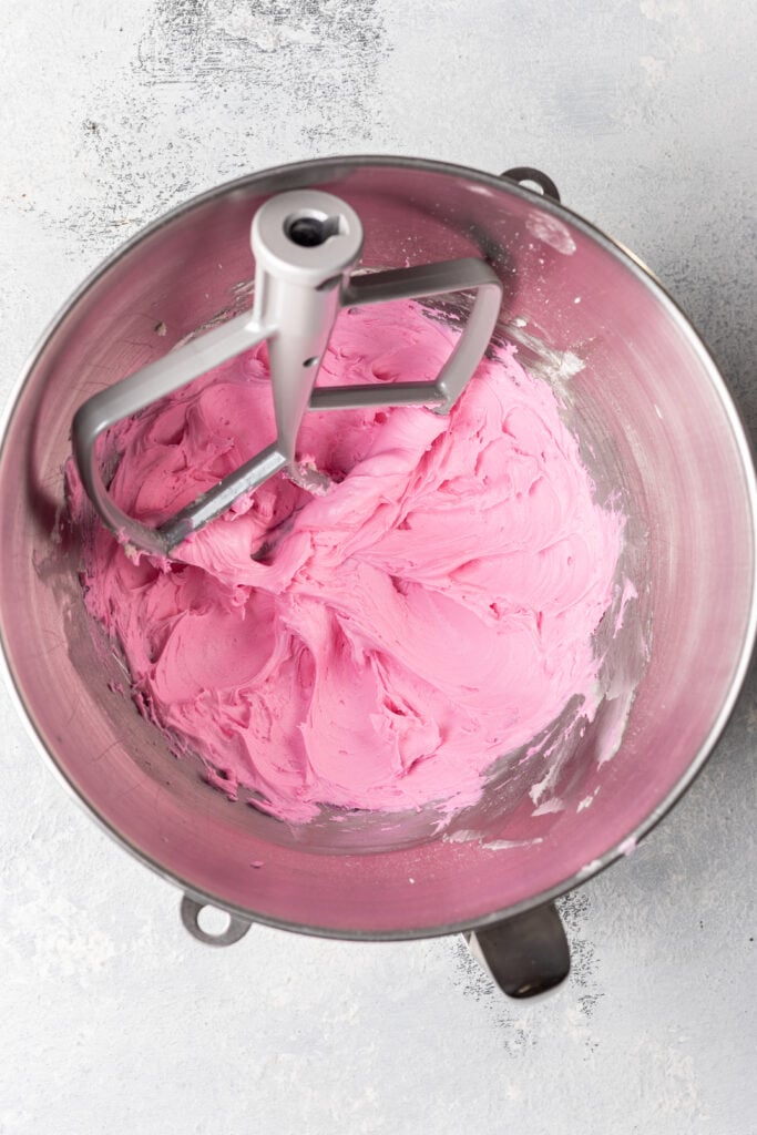 pink frosting in a bowl with mixer blade