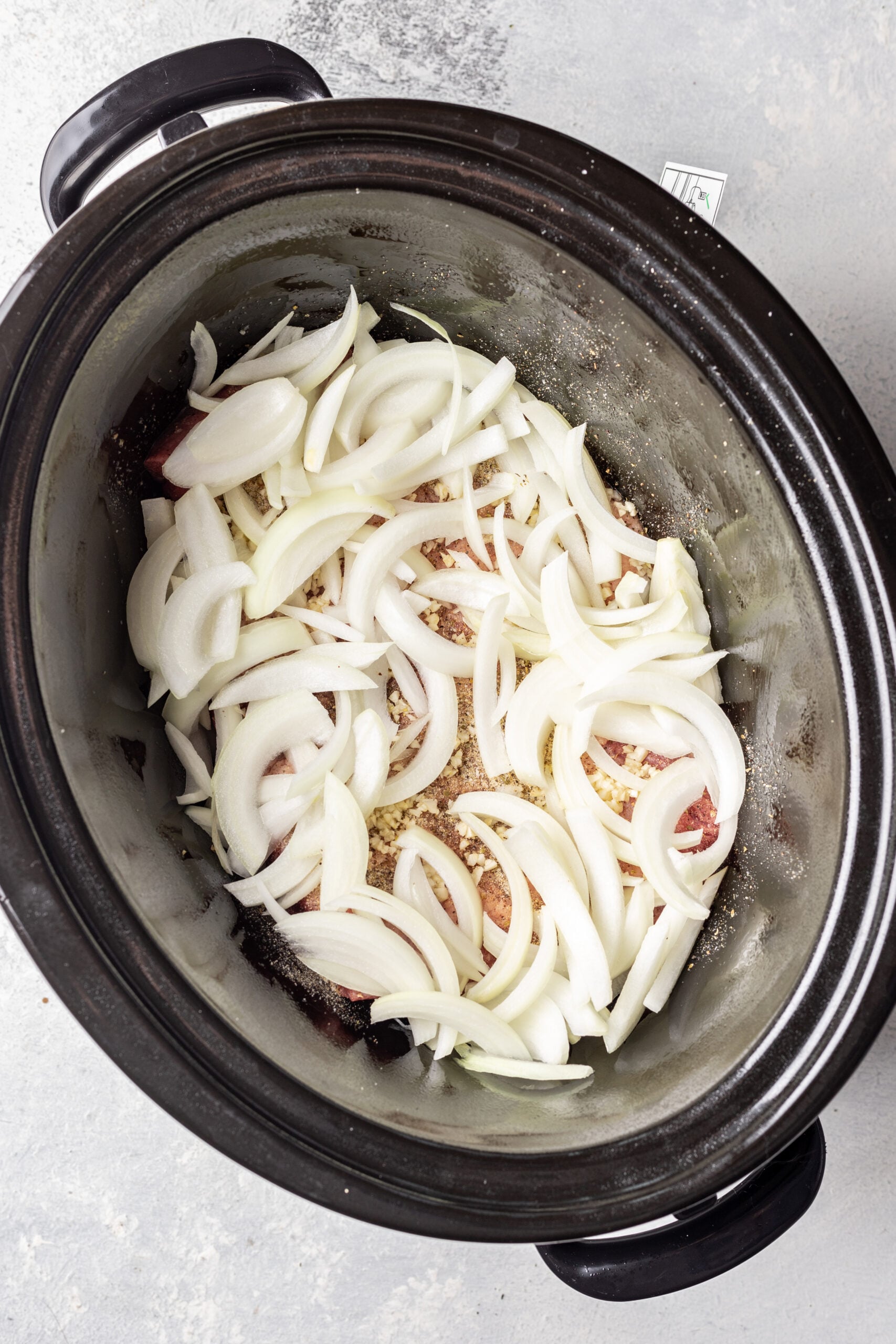 slow cooker with a brisket covered in sliced onions
