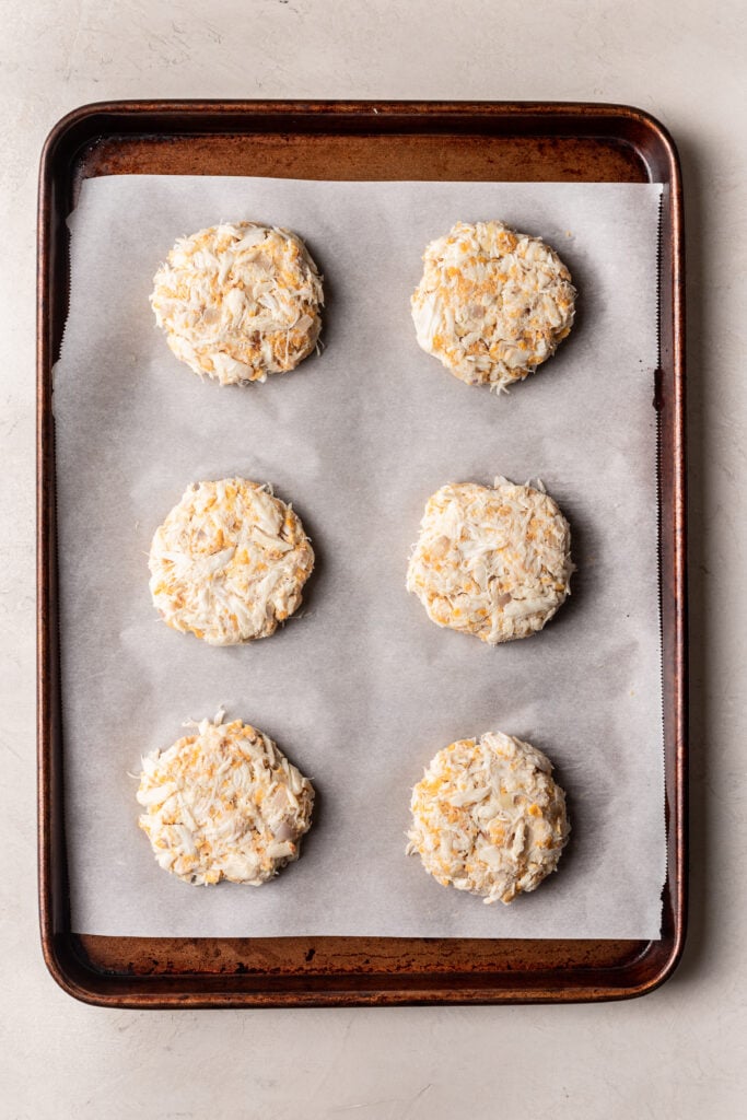 uncooked crab cakes on a parchment lined baking sheet