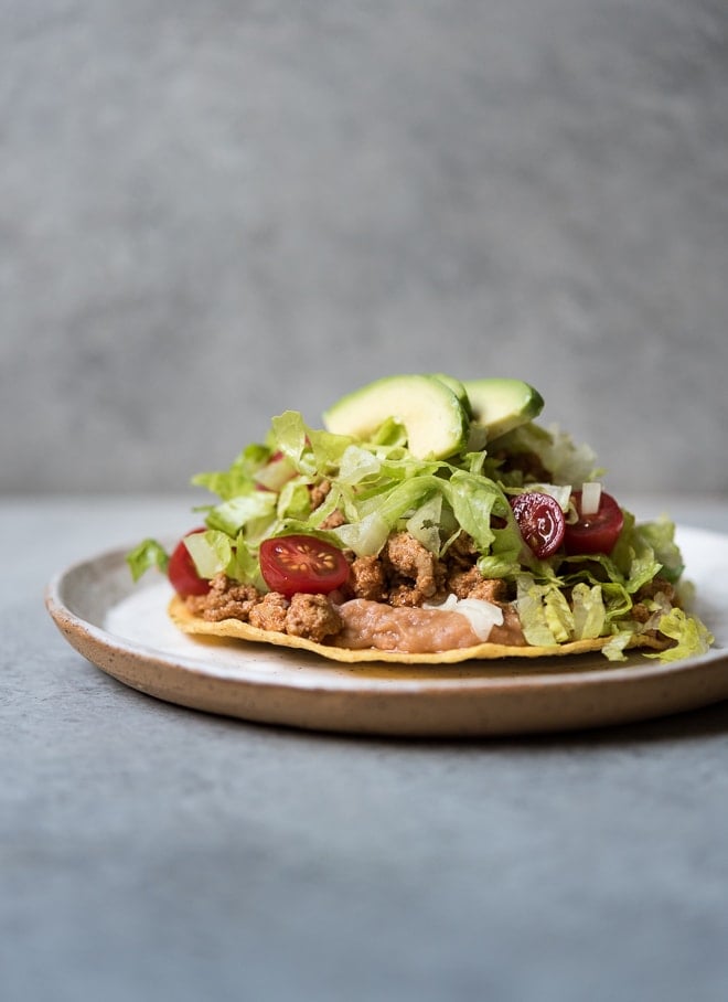 refried beans, ground turkey, lettuce, tomato and avocado on a crispy tostada