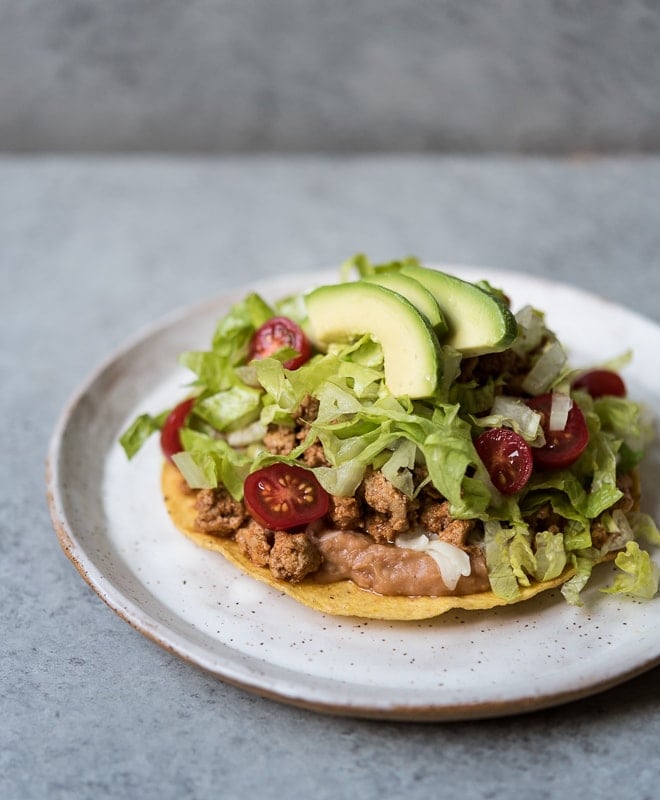 refried beans, ground turkey, lettuce, tomato and avocado on a crispy tostada
