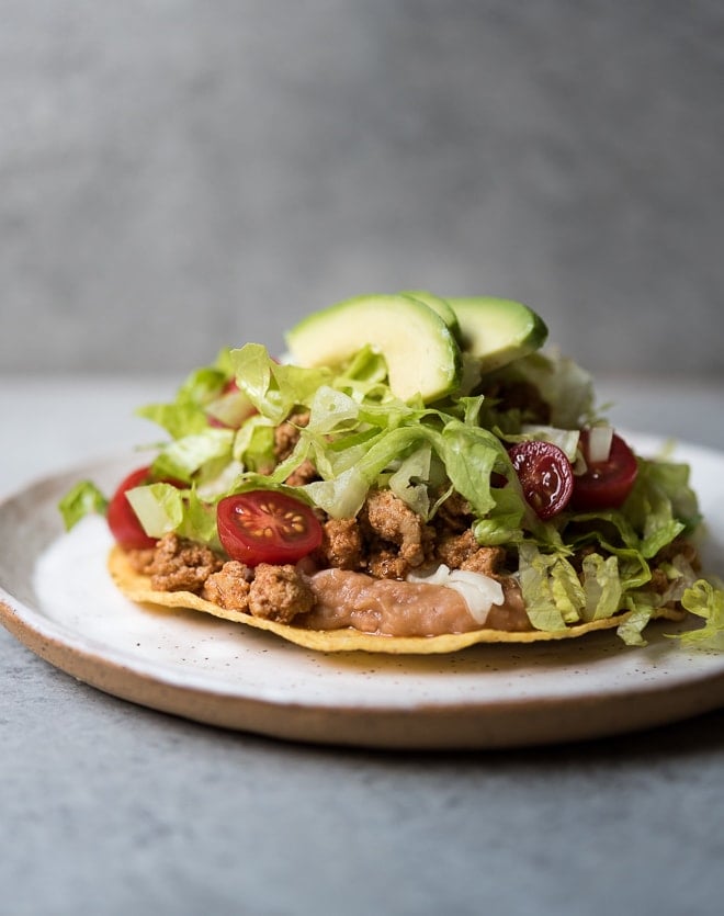 refried beans, ground turkey, lettuce, tomato and avocado on a crispy tostada