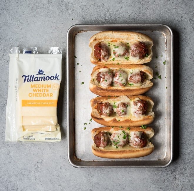4 meatball subs with melted cheese on a sheet pan