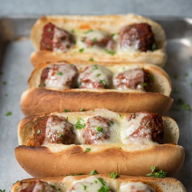 4 meatball subs with melted cheese on a sheet pan
