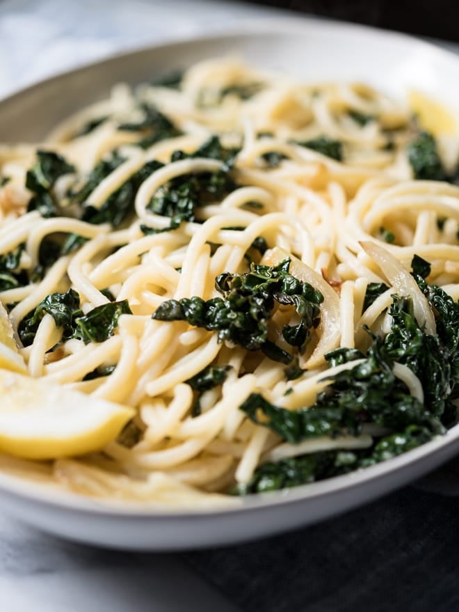 Lemony Pasta with Kale and Parmesan on a platter with a lemon