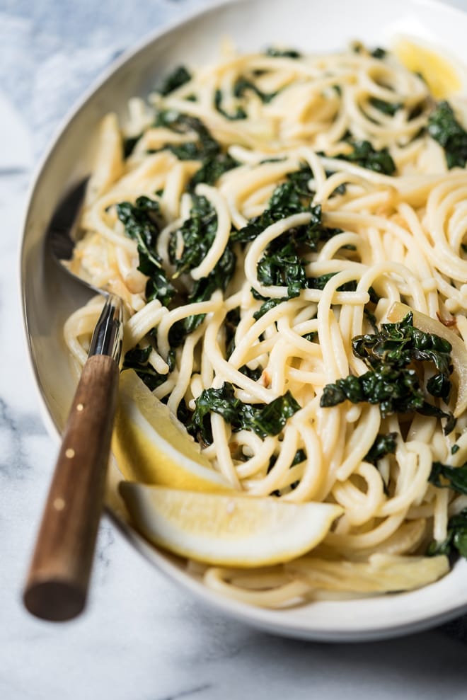 pasta with lemon and kale on a platter with a serving spoon