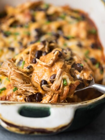 chicken enchilada casserole with back beans on a serving spoon