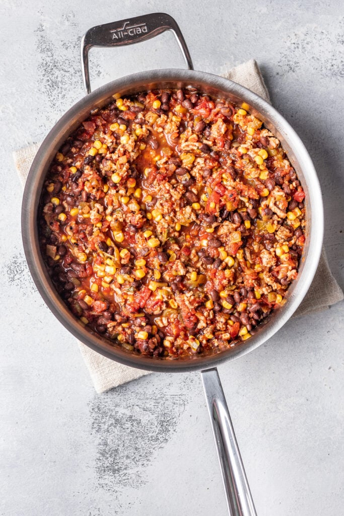 ground meat in a pan with spices and tomatoes and corn