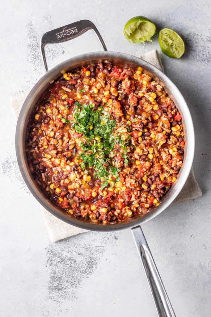ground taco meat in a pan with spices, corn and herbs