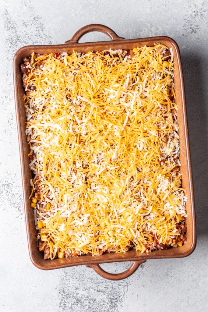 taco bake in a baking dish covered with shredded cheese
