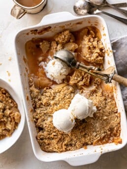 overhead apple crisp in rectangular pan with three scoops of vanilla ice cream and coffee