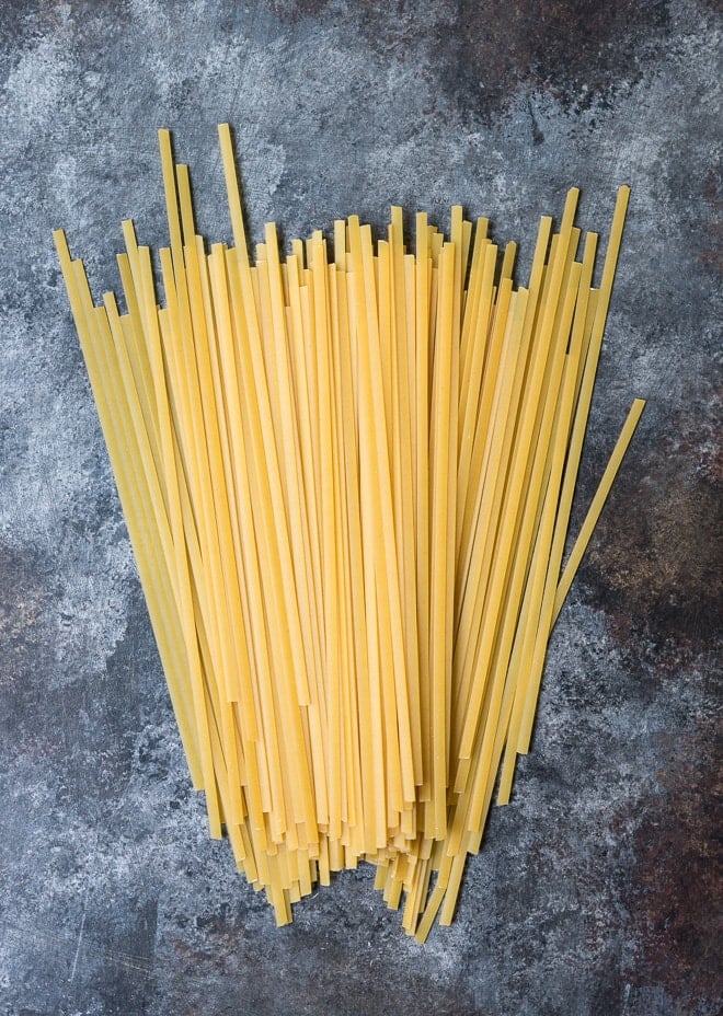 raw fettuccine noodles on a dark board