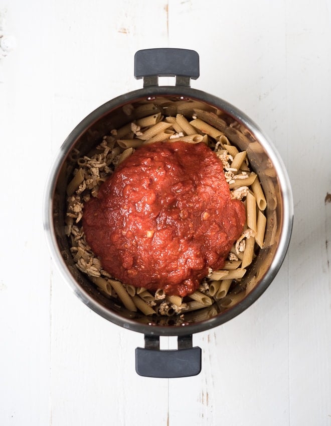 pasta and ground turkey in an instant pot with tomato sauce on top