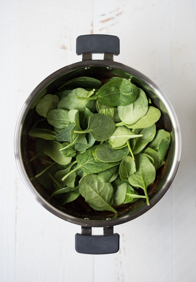 instant pot with spinach on top of cooked pasta