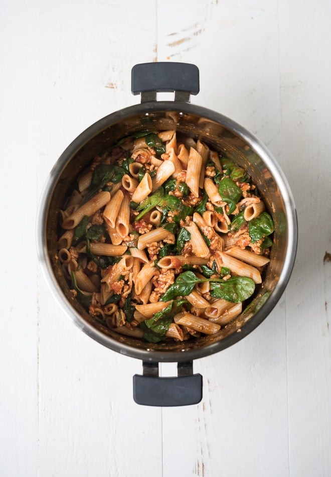 instant pot with cooked pasta, ground turkey, tomato sauce and spinach