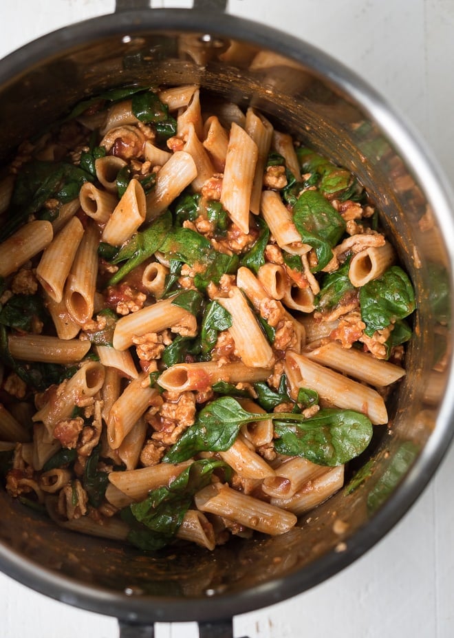 instant pot with cooked pasta, ground turkey, tomato sauce and spinach
