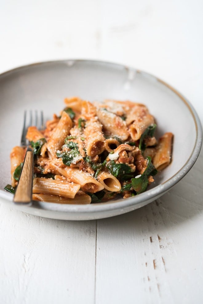 bowl of pasta with spinach, cheese and tomato sauce