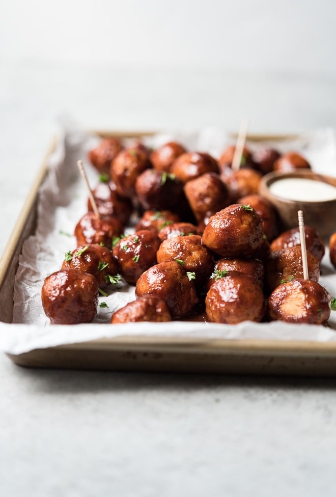 shot of meatballs piled on a sheet pan with toothpicks in the meatballs