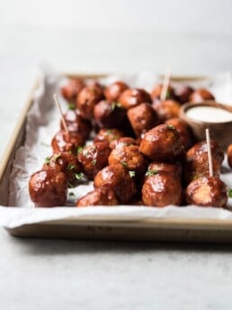 shot of meatballs piled on a sheet tray with a toothpick