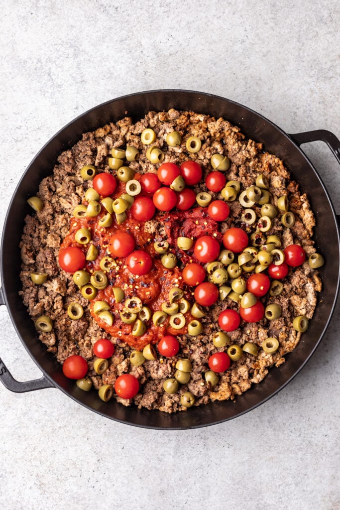 ground meat, tomatoes and olives in a pan
